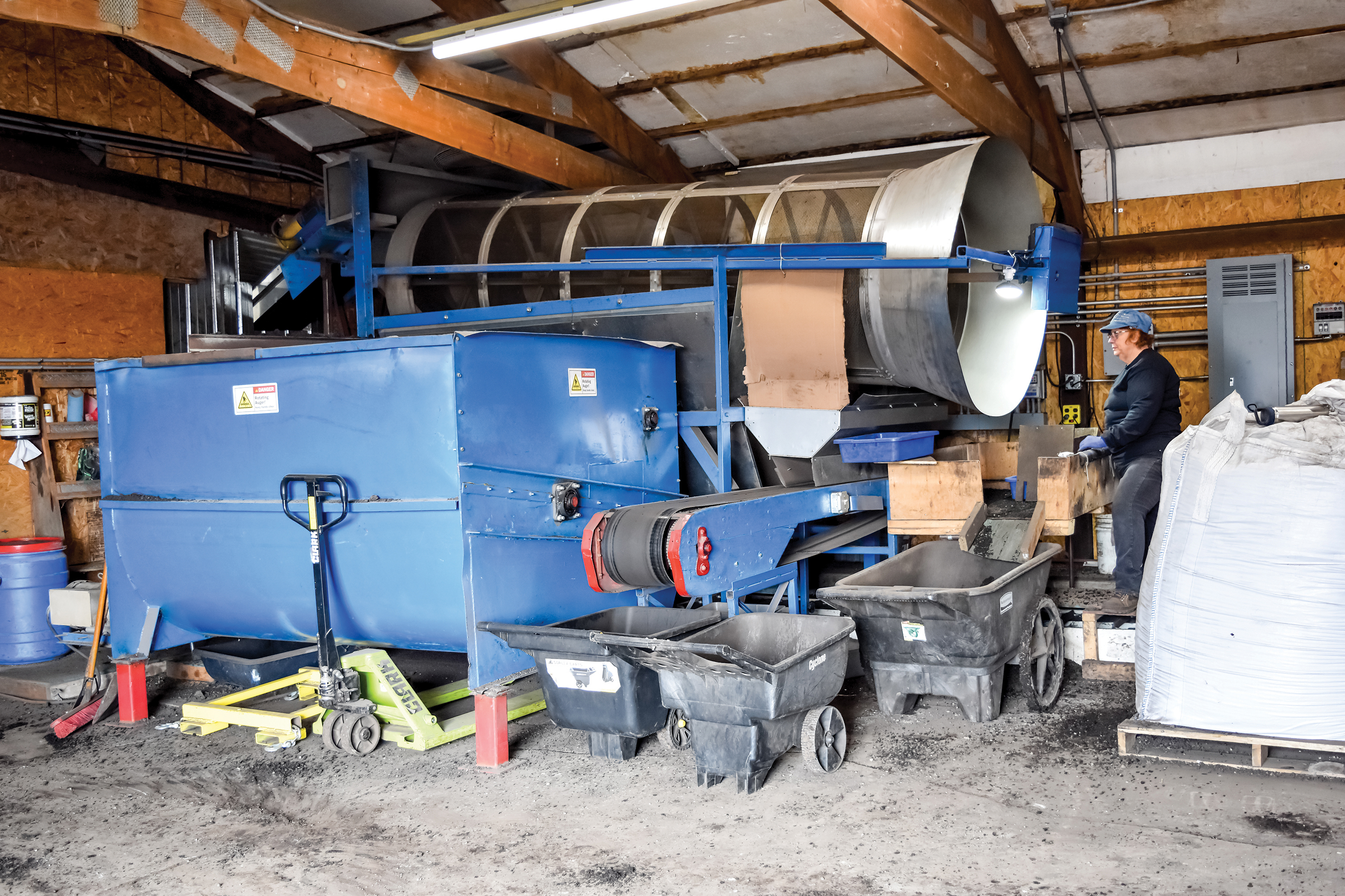 Worm bedding is mixed in a repurposed feed mixer. Worms travel through the large bell where a series of screens separates thecastings from the undigested worm bedding.