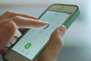 Finger touch number on smartphone to make a call, close up