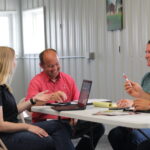 A group of Farm Bureau members sit around a table discussing local agriculture issues.