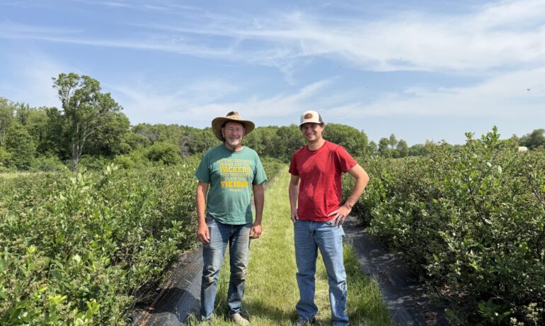 two men stand in a berry patch