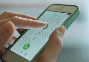 Finger touch number on smartphone to make a call, close up